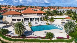 A resort with a central swimming pool, lounge areas, and a landscaped garden.