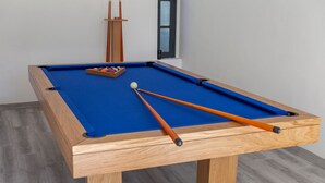 A pool table with a blue felt surface, wooden frame, and orange cues. - Villa Cayo Coco (Portimão)