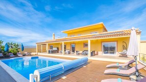 Una piscina con lettini e un’area patio coperta.