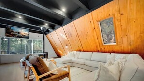 A modern living room with a wooden accent wall, a large sectional sofa, a brown leather chair, and a fireplace.
