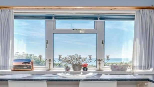 A room with a large window, a table with chairs, and decorative items. - Brighton - 3 Beds - Pet Friendly - Sea View (Brighton)