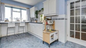 A kitchen with white cabinets, a wooden countertop, and a tiled floor. - Brighton - 3 Beds - Pet Friendly - Sea View (Brighton)