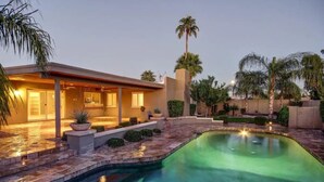 A modern house with a swimming pool, a covered patio, and a well-maintained garden.