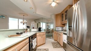 A modern kitchen with stainless steel appliances, wooden cabinets, and a large window providing natural light. - Ocean View 7th floor Condo on Daytona Beach!

 (Daytona Beach Shores)