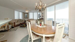 A spacious living room with a dining area, large windows, and a balcony. - Ocean View 7th floor Condo on Daytona Beach!

 (Daytona Beach Shores)