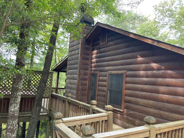 A wooden cabin with a balcony, surrounded by trees.