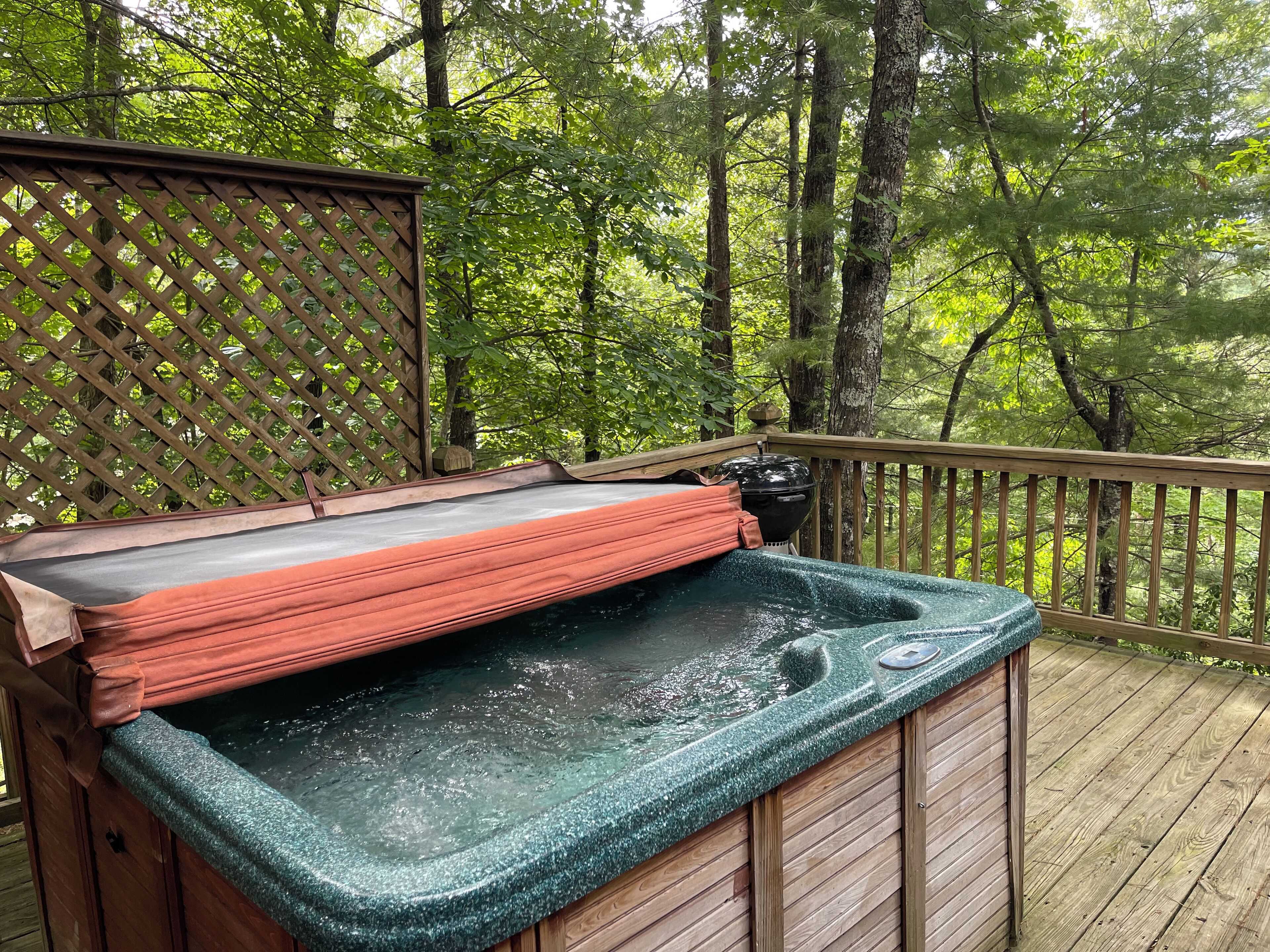 A hot tub on a wooden deck surrounded by trees.