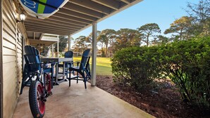 Une terrasse extérieure avec une table et des chaises, un vélo et une vue sur un terrain de golf.
