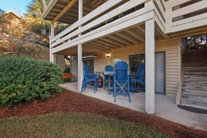 A covered patio with blue chairs and a table, surrounded by a wooden deck and a well-maintained garden. - 🌴 Winter Deal ❄️ Golf Cart-Heated Pool-FAB Reno- Seascape 22A🌊 (Miramar Beach)