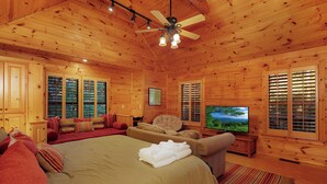 Una habitación de cabaña de madera con una cama grande, un televisor y un sofá.