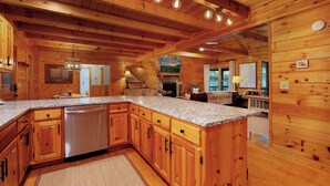 Una cocina amplia con armarios de madera, encimera de granito y lavavajillas de acero inoxidable.
