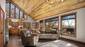 Ein geräumiges Wohnzimmer mit hoher Decke, großen Fenstern und einem gemütlichen Kamin.
