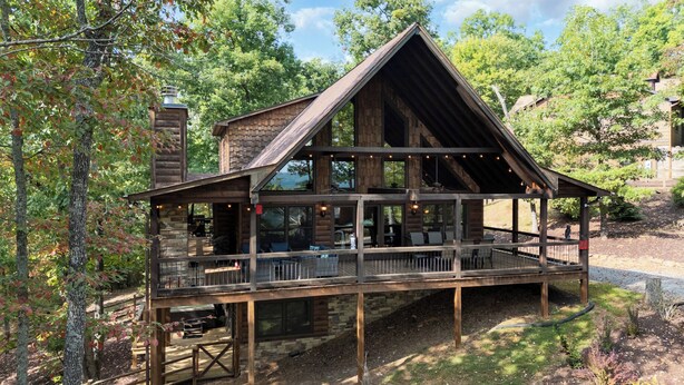 Una baita rustica con veranda in legno e numerose finestre, immersa nel verde.