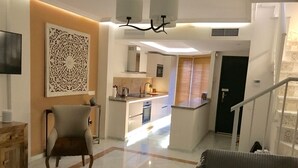 Un salon moderne avec un canapé, une table basse et un téléviseur. Il y a également un coin cuisine avec une table à manger et des chaises.