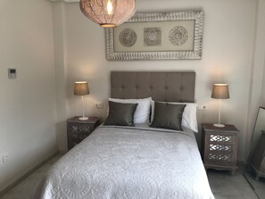 Un dormitorio ordenado con una cama grande, dos mesitas de noche y un adorno decorativo sobre la cama.