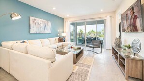 A modern living room with a sofa, coffee table, and a glass door leading to an outdoor patio.