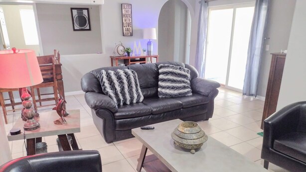 A living room with a black leather sofa, a coffee table with a decorative bowl, and a lamp on a side table. - TERRA NOVA Spacious 4-bedroom house in Phoenix AZ, 7 minutes from Downtown. (Phoenix)
