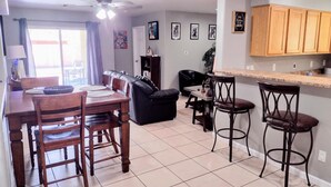 A dining area with a table and chairs, a sofa, and a kitchen area with wooden cabinets and a countertop. - TERRA NOVA Spacious 4-bedroom house in Phoenix AZ, 7 minutes from Downtown. (Phoenix)