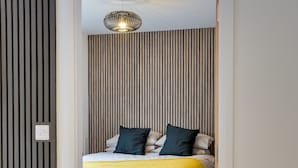 Une chambre à coucher avec un lit, un luminaire suspendu et un radiateur.