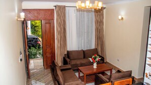 A living room with a sofa, armchairs, a coffee table, and a chandelier. - VvEK BED AND BREAKFAST APARTMENT (Arusha)