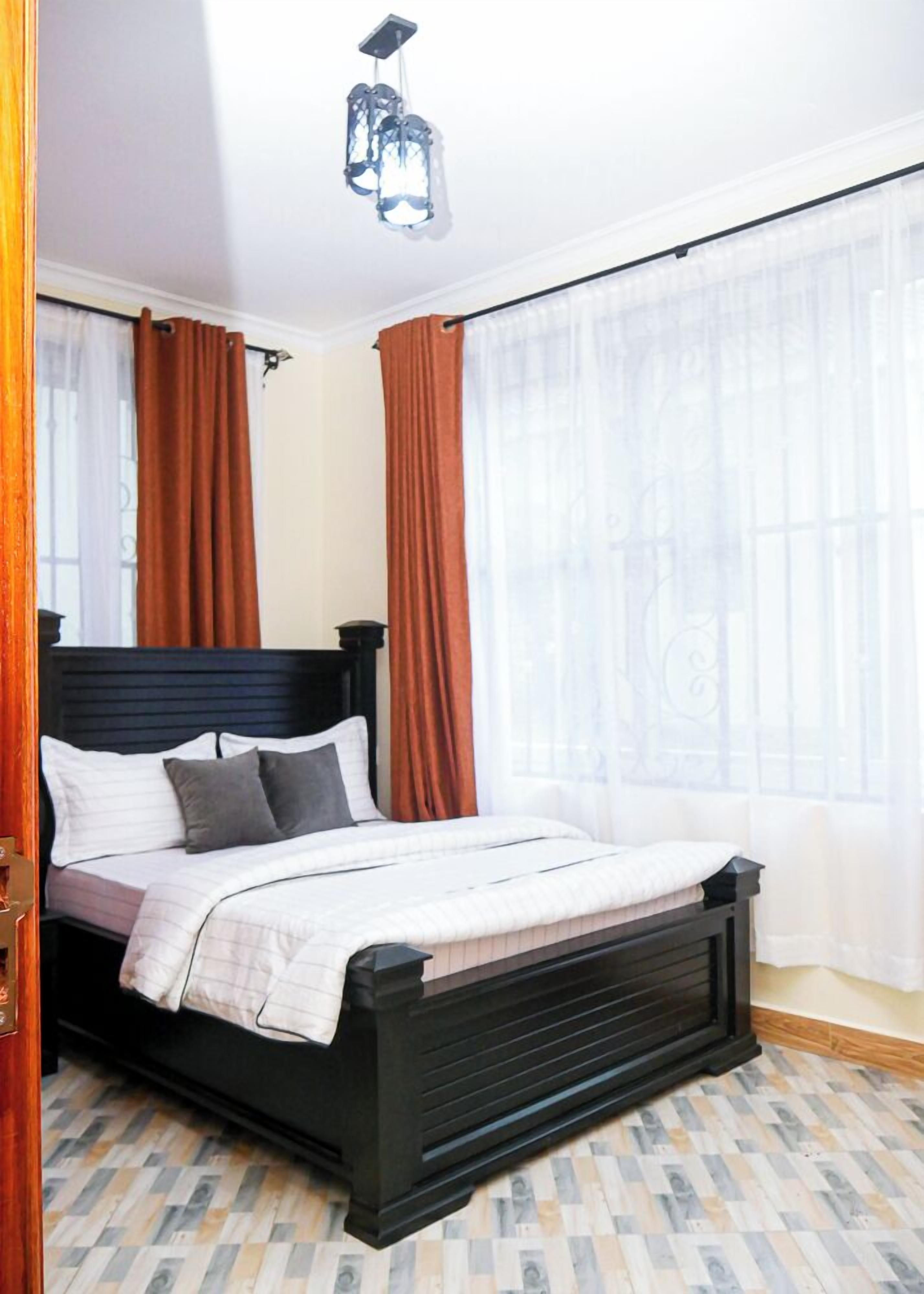 A bedroom with a bed, curtains, and a chandelier.