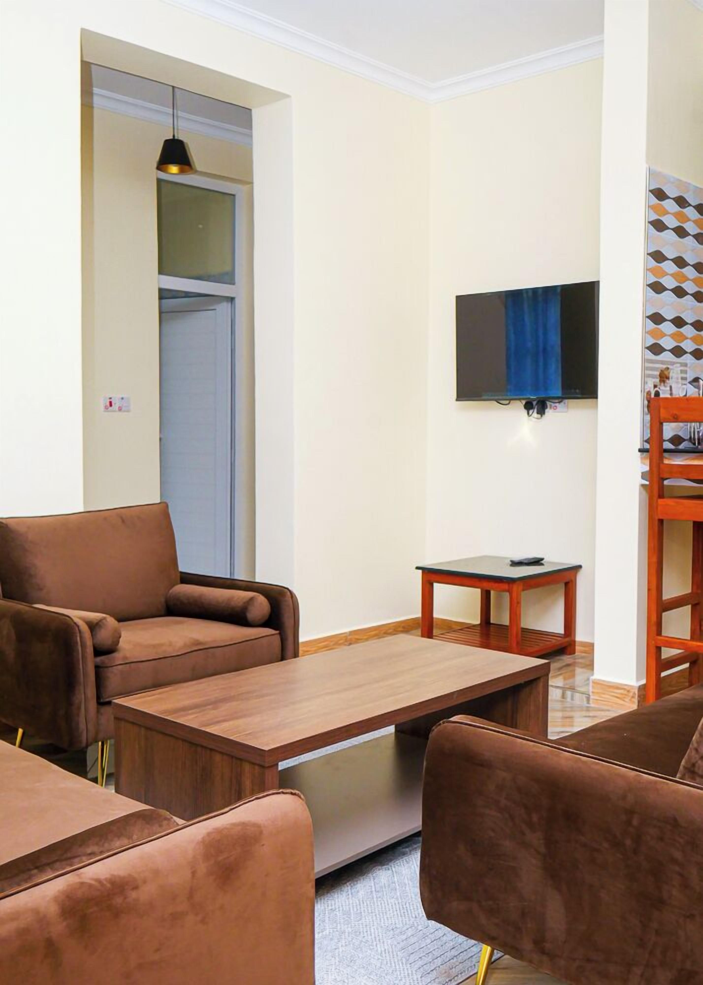 Uma sala de estar com um sofá, uma mesa de centro e uma televisão na parede.