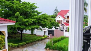 A courtyard with a paved walkway, surrounded by lush greenery and white buildings with red roofs. - VvEK BED AND BREAKFAST APARTMENT (Arusha)