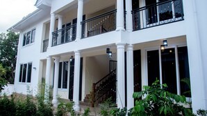 A two-story house with a balcony, large windows, and a staircase. - VvEK BED AND BREAKFAST APARTMENT (Arusha)