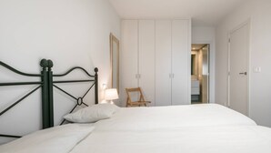 Quarto com cama, mesa de cabeceira, cadeira e guarda-roupa.