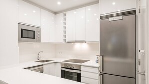 Uma cozinha moderna com armários brancos, eletrodomésticos de aço inoxidável e micro-ondas embutido.