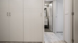 Um corredor com um guarda-roupa, um banheiro e uma porta que dá para outro quarto.