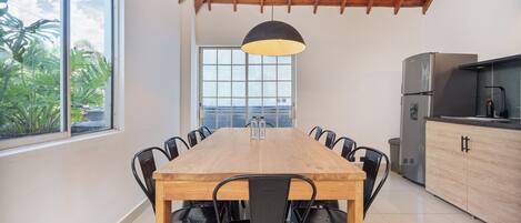 A modern kitchen with a wooden dining table, black chairs, a large window, and a view of the outdoors.