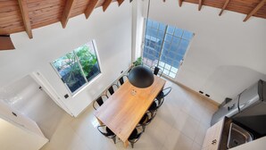 Eine moderne Küche mit einem Holztisch, schwarzen Stühlen und einem großen Fenster.