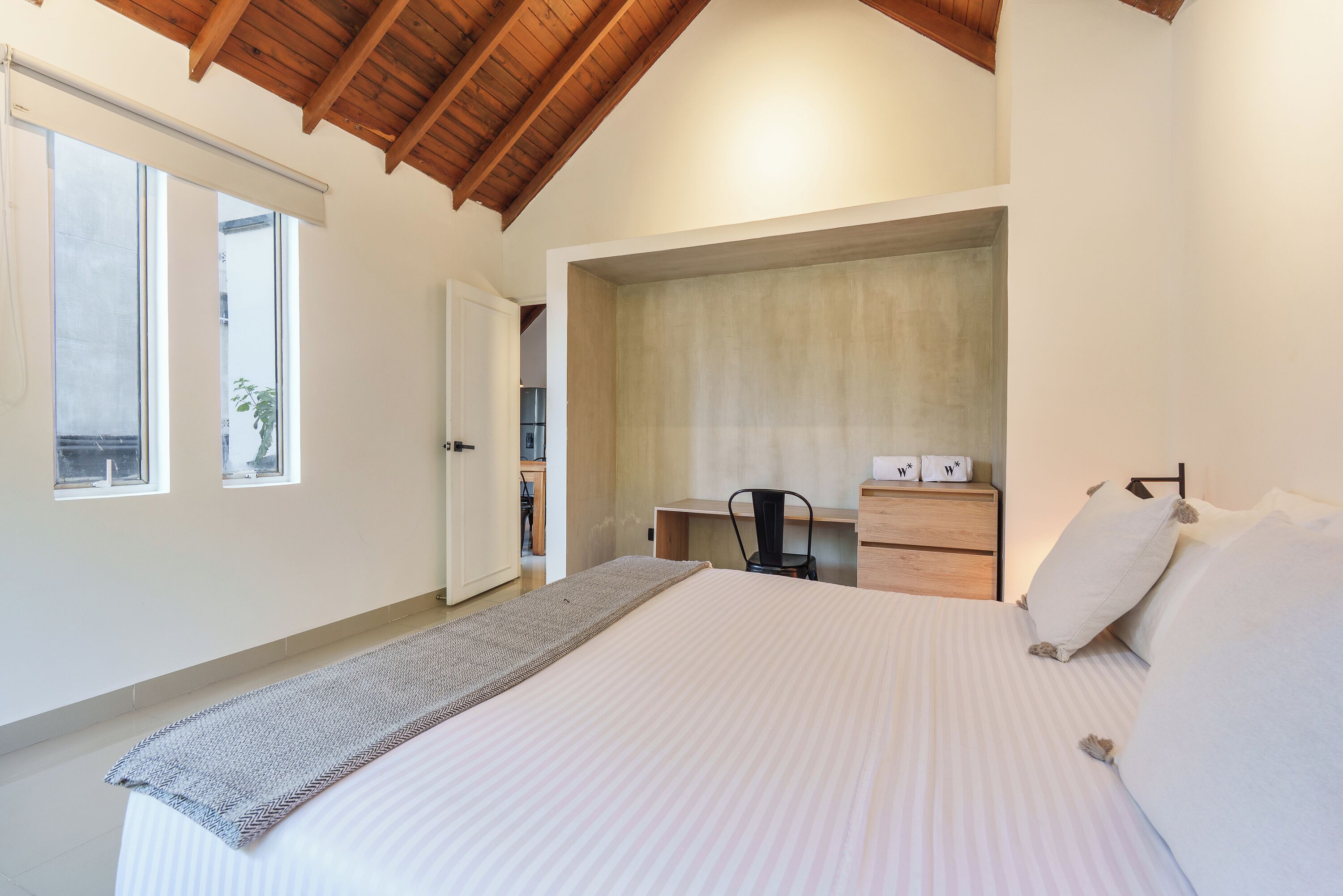 A bedroom with a bed, a desk, and a chair.