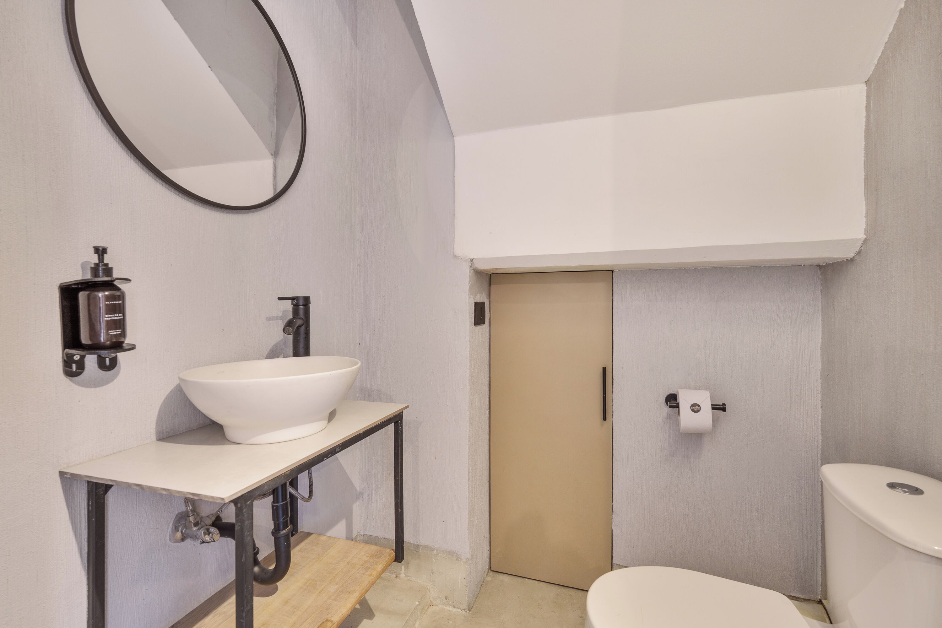 Ein Badezimmer mit weißem Waschbecken, einem Spiegel, einer Toilette und einer Tür.