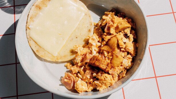 A breakfast plate with scrambled eggs, toast, a glass of orange juice, and a cup of coffee on a checkered tablecloth. - Hotel Santa Ana (Medellín)
