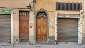 A street view with a wooden door, a closed metal shutter, and a sign for a halal market. - Mamo Florence - Sacha Apartment (Florence)
