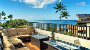 A balcony with a sofa, a glass-top table, and a view of the ocean. - Summer Deal Oceanfront Poipu Condo with Heated Pool and Lanai (Koloa)