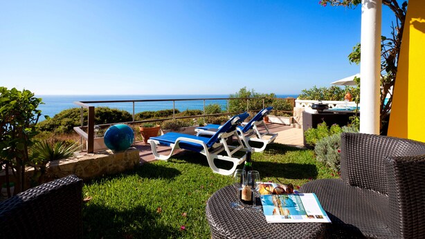 Un patio con sillones de descanso, una mesa redonda y vista al mar.