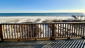 Une terrasse en bois offrant une vue sur une plage et l’océan.