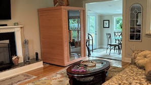 A living room with a fireplace, a wooden cabinet, a round coffee table, and a floral sofa. - Come visit our “Sweet Retreat at the End of the Street” where you can relax!!! (Summerville)