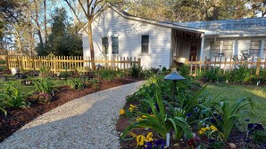 A house with a gravel pathway leading to a porch, surrounded by a wooden fence and various plants. - Come visit our “Sweet Retreat at the End of the Street” where you can relax!!! (Summerville)