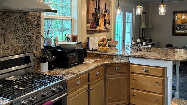 A kitchen with granite countertops, a stainless steel stove, wooden cabinets, and a large window. - Come visit our “Sweet Retreat at the End of the Street” where you can relax!!! (Summerville)