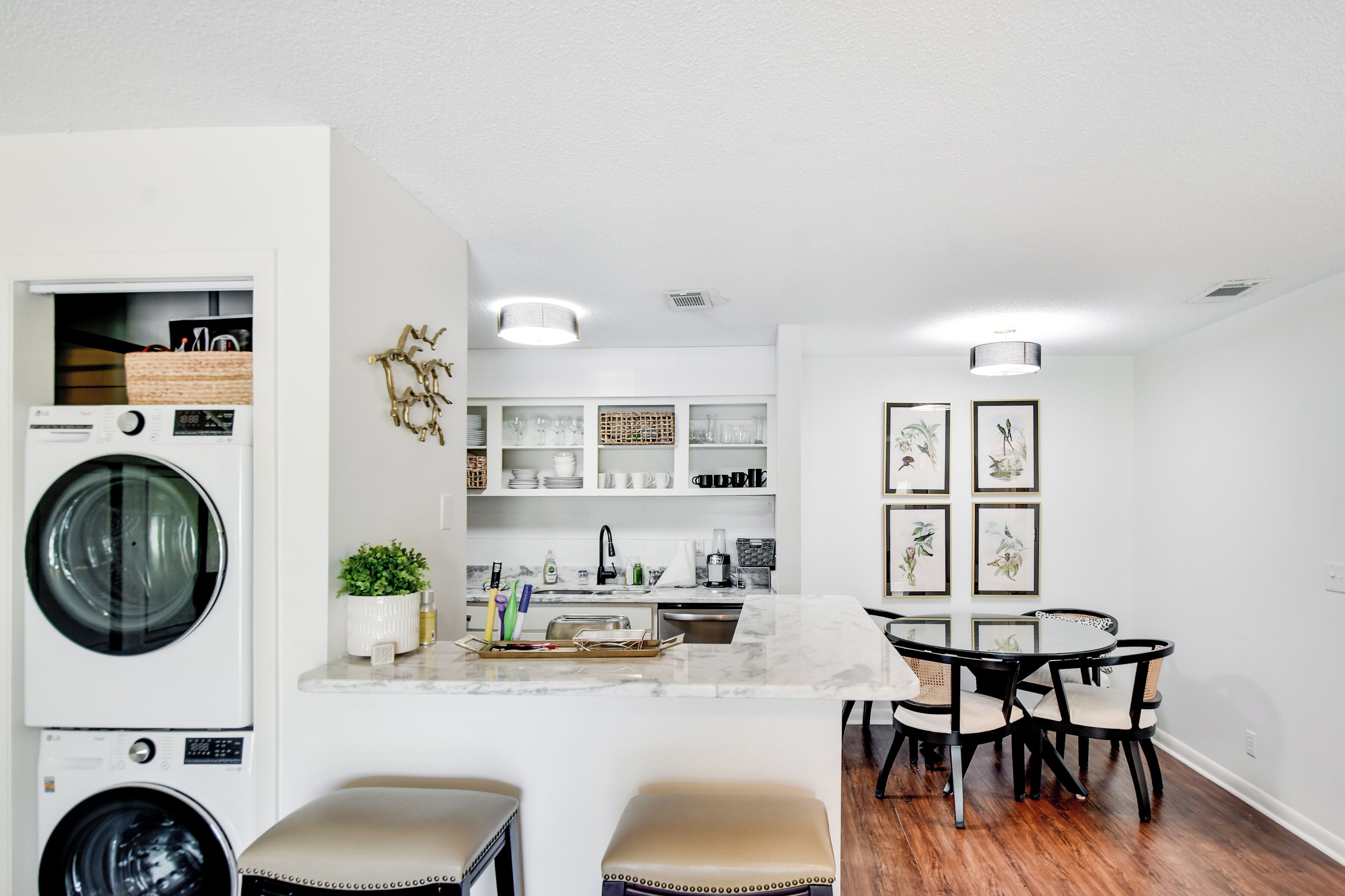 A modern kitchen with built-in appliances, a marble island, and a dining area with a round table and chairs.