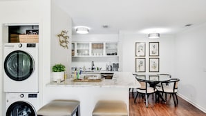 Uma cozinha moderna com eletrodomésticos embutidos, uma ilha de mármore e uma área de refeições com mesa e cadeiras redondas.