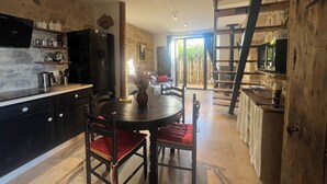 Una cocina rústica con comedor, paredes de piedra y una escalera de madera.