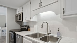 A modern kitchen with white cabinets, stainless steel appliances, and a double sink.