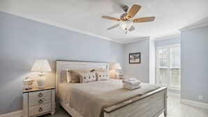 A bedroom with a bed, nightstands, a ceiling fan, and a window with blinds.