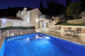 Ein moderner Poolbereich mit einem klaren, blauen Pool, einer Steinmauer und Sitzgelegenheiten im Freien.