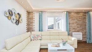 Un soggiorno moderno con un divano angolare beige, un tavolino da caffè bianco e decorazioni a parete.